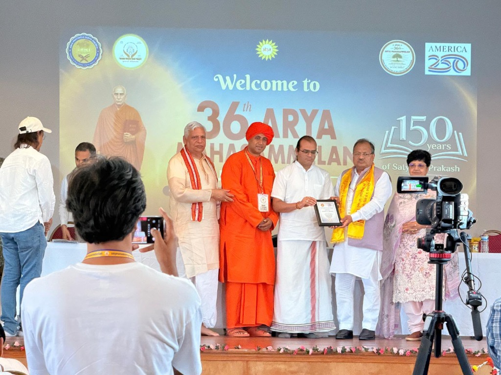 36th Arya Mahasammelan National Felicitation — Acharya Varun Dev Sharma honored on stage at the 36th Arya Mahasammelan celebrating 150 years of Satyarth Prakash.